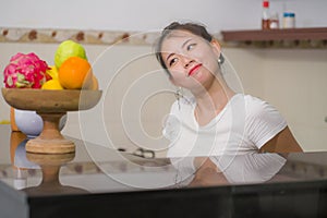 Lifestyle portrait of young beautiful and happy Asian Chinese woman posing relaxed at home kitchen smiling cheerful and sweet