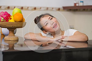 Lifestyle portrait of young beautiful and happy Asian Chinese woman posing relaxed at home kitchen smiling cheerful and sweet