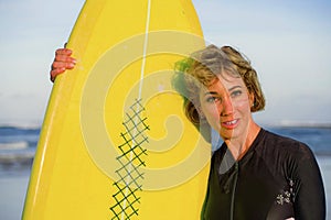 Lifestyle portrait of young beautiful and happy surfer woman holding yellow surf board smiling cheerful enjoying summer holid