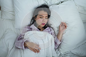 Lifestyle portrait of young beautiful and sweet Asian Chinese girl on her 20s alone at home sleeping relaxed wearing pajamas lying