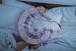 Lifestyle portrait of young beautiful and sweet Asian Chinese girl on her 20s alone at home sleeping relaxed wearing pajamas lying