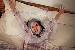 Lifestyle portrait of young beautiful and sweet Asian Chinese woman in bed feeling happy and relaxed wearing cute pajamas enjoying