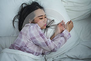 Lifestyle portrait of young beautiful and sweet Asian Korean girl on her 20s alone at home sleeping relaxed wearing pajamas lying