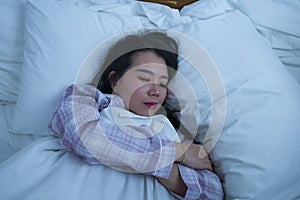 Lifestyle portrait of young beautiful and sweet Asian Korean girl on her 20s alone at home sleeping relaxed wearing pajamas lying