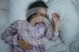 Lifestyle portrait of young beautiful and sweet Asian Korean girl on her 20s alone at home sleeping relaxed wearing pajamas lying