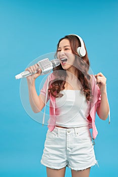 Lifestyle portrait of young cute and happy Asian student girl singing online karaoke song with microphone
