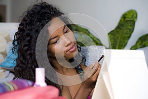 Lifestyle portrait of young happy and beautiful black african American woman applying face make up using eyebrow profiler pencil l