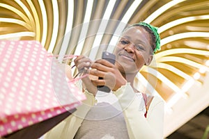 Lifestyle portrait of young happy and beautiful black African American woman holding shopping bags buying at mall fashion store