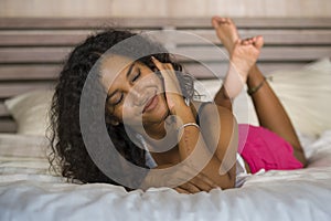 Lifestyle portrait of young happy and gorgeous black latin American woman posing and playful at home bedroom lying relaxed on