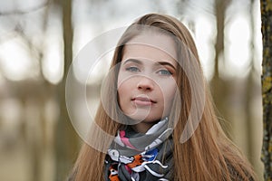 Lifestyle portrait of young and pretty adult woman with gorgeous long hair posing in city park with shallow depth of field