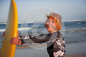 Young beautiful and happy surfer girl holding yellow surf board smiling cheerful enjoying summer holidays in tropical beach w