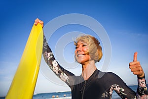 Young beautiful and happy surfer woman holding yellow surf board smiling cheerful enjoying summer holidays in tropical beach