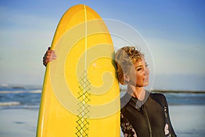 Lifestyle portrait of young beautiful and happy surfer woman holding yellow surf board smiling cheerful enjoying summer holid