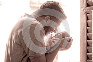 Lifestyle shot in black and white of young and happy man holding tenderly in his arms adorable newborn baby girl  in father and