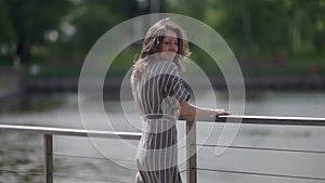 lifestyle shot, walking woman over embankment of lake in small town, happy smiling lady