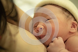 Lifestyle shot of woman holding adorable newborn baby girl skin on skin  immediately after birth laying happy on hospital bed in