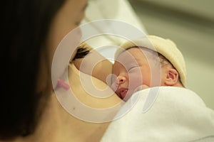 Lifestyle shot of woman holding adorable newborn baby girl skin on skin  immediately after birth laying happy on hospital bed in