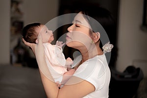 Lifestyle shot on young and happy Asian Chinese woman holding tenderly her adorable newborn baby girl in her arms in mother and