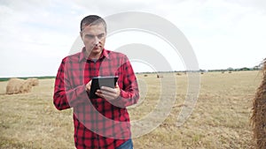Lifestyle smart farming agriculture concept. man farmer studying a haystack in a field on digital tablet. slow motion