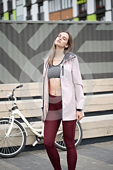 Lifestyle sport concepte. Portrait of young woman with vintage bike in city parking. Nature color toning for design