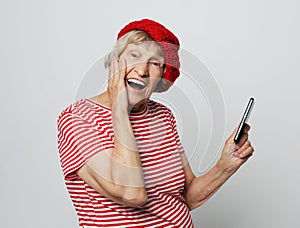Lifestyle, tehnology  and people concept: old granny looks at her phone and is surprised