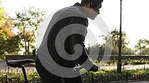 Lifestyle, transport, technology and people concept - young man with headphones starts riding bicycle on city street