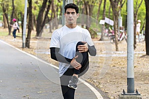 Lifestyle wellness healthy exercise activity concept. Happy sportsman stretching leg up warming body before jogging in the park