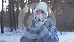 Lifestyle a woman in a down jacket and a white hat walks in a winter Park on a Sunny day, walking in the fresh air is good for hea