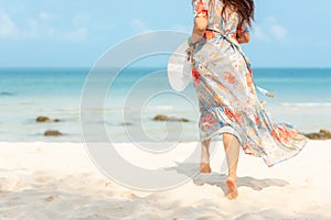 Lifestyle woman wearing fashion  dress summer running on the sandy ocean beach. Happy woman enjoy and relax vacation.