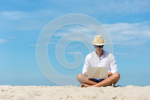 Lifestyle young asian man working on laptop while sitting on the beautiful beach, freelance working on holiday summer, blue sky ba