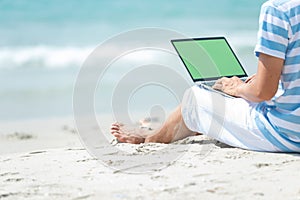 Lifestyle young asian man working on laptop while sitting chill on the beautiful outdoor beach, freelance working social on holida photo
