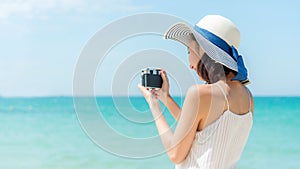 Lifestyle young woman relax on the summer beach.  Asia tourism people holding camera and take a photo