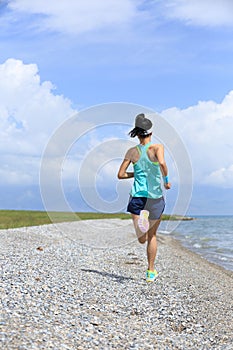 Lifestyle young woman runner running on seaside road