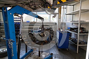 lift crane with car engine in auto service workshop