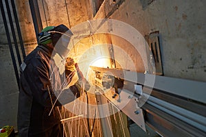 Lift worker welding elevator fasteners in lift shaft photo