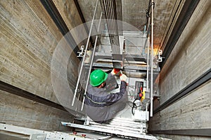 Lift machinist repairing elevator in lift shaft