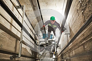 Lift machinist repairing elevator in lift shaft photo