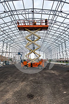 Lift with platform work in warehouse hangar construction field.