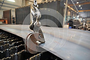 Lifting chains and hooks for loading sheet metal. Placing metal on a plasma cutting machine