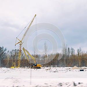 Lifting construction crane on a Construction site in a field near a forest in winter season