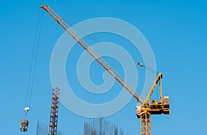 Lifting crane at building construction site with clear blue sky