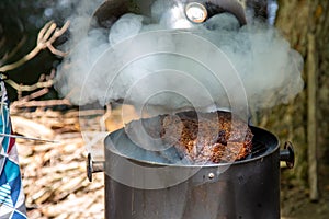 lifting the lid to check on a large beef brisket on a smoker