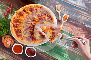 Lifting a piece of Pizza served on wood table with ketch up photo