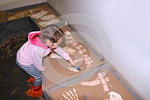 Liftle girl in pink with brush in hand digs bones