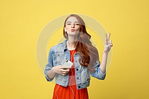 Liftstyle: Portrait of a pretty smiling caucasian woman in headphones listening to music and showing peace gesture