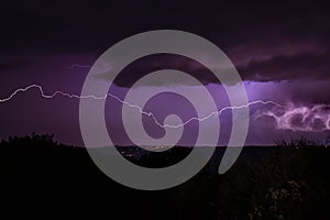Lighning bolt over night sky in central europe. Huge lightning in a purple clouds over a night city. Storm at night