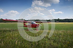 Light aircraft. Light red school airplane on airport grass