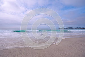 Light airly seascape in blue and pink colors. Wide sandy beach, sea waves, and cloudy sky