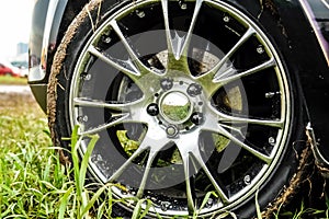 Light alloy wheel of the car is dirty with dirt. The car is on the field