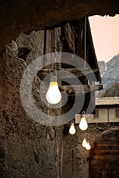Light art installation an old alpine court. Wooden and stone architecture Bormio, Italy